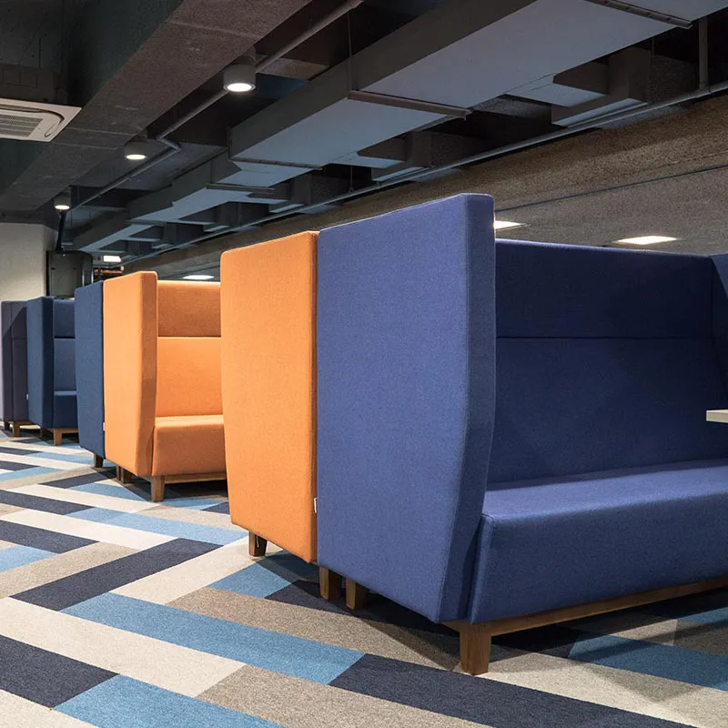 Tall booths made up of blue and orange chairs on patterned carpet